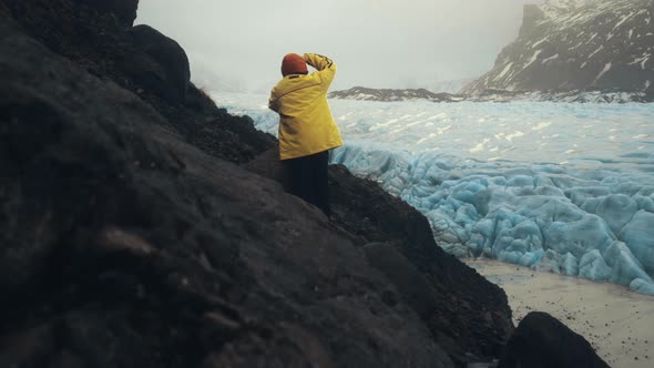 Tourist taking photos of picturesque glacier