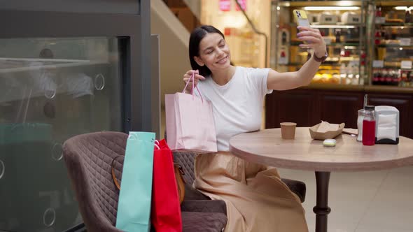 Charming Fashion Blogger Taking Selfie with Paper Bag at Shopping Mall