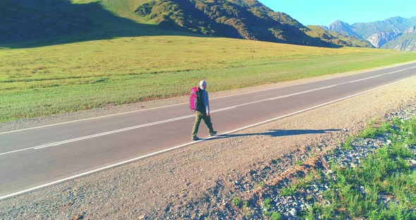 Flight Over Hitchhiker Tourist Walking on Asphalt Road