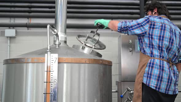 Man Working at a Brewery Opening One of the Distillery Stills