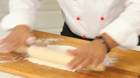 Kneading Dough with Rolling Pin on Wooden Table