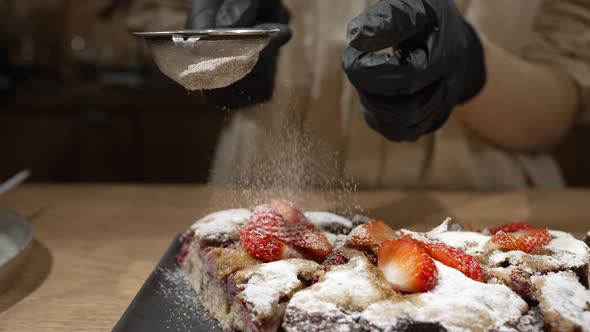 Pastry Cook Sprinkles Strawberry Cakes with Sugar Powder