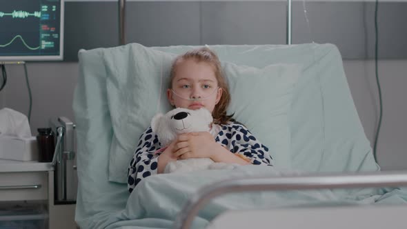 Portrait of Lonley Sick Little Child Resting in Bed Holding Teedy Bear in Hands Looking at Camera