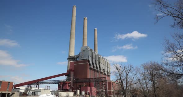 Coal burning power plant with three smoke stacks and clouds time-lapse video.