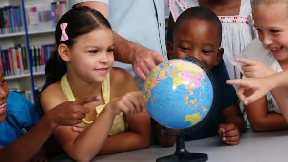 Teacher discussing globe with kids in library