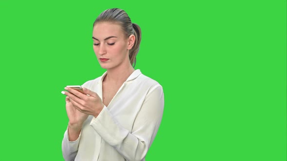 Pensive Business Woman Using Mobile Cell Phone Reading Message, Wear White Suit on a Green Screen