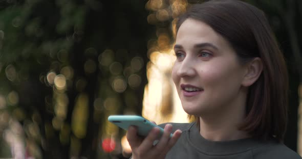 Happy Girl Using a Smart Phone Voice Recognition Audio Message Function on Line Walking on a Street