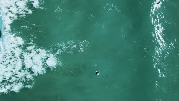 A surfer waiting to catch a wave. Close to wide drone-shot.