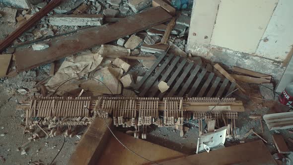 Broken Parts of a Piano Lie in a Ruined Building Amidst Garbage