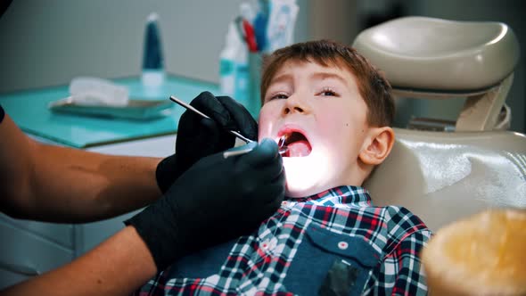 A Little Stressful Boy with Damaged Baby Teeth Having a Treatment in Modern Dentistry - Examination