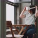 Young woman sitting on balcony putting on virtual reality goggles - VideoHive Item for Sale
