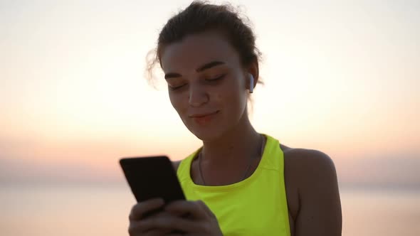 Happy Young Woman Chatting in Smartphone in the Headphones