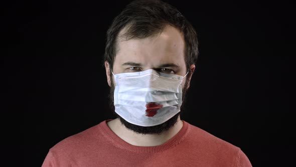 Sick Man in Medical Mask with Blood on It Puts on New Mask. Covid-19 Concept