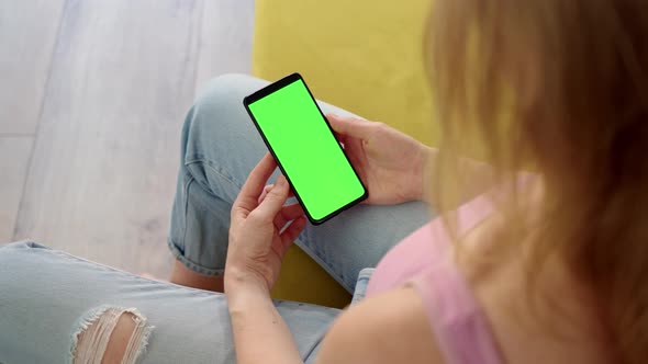Rear View of Phone with Green Screen Chroma Key in Hands of Blonde in Pink Top