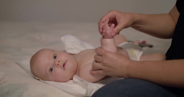 View of Massaging Cute Little Baby's Arm and Palm on Bed