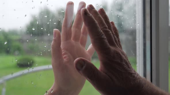 Woman And Old Man Touch Palms Of Their Hands Through Glass Window Closeup