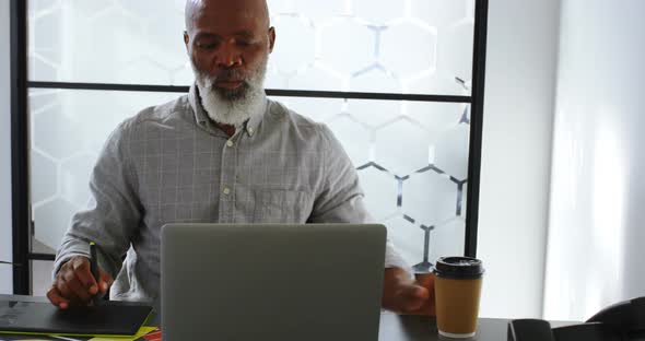 Businessman having coffee while using graphic tablet on desk 