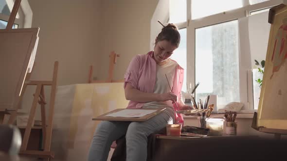 Caucasian Woman Artist Working on a Painting in Bright Daylight Studio