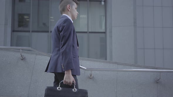 Cute Little Boy Wearing a Business Suit with Case Walking in the City