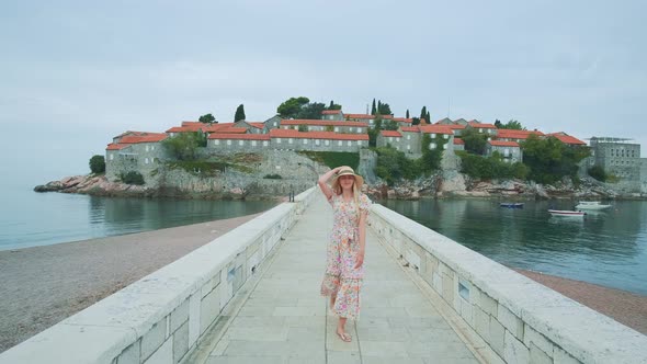 A Long Stone Bridge with Pretty Woman Walking From the Island Washed By the Sea