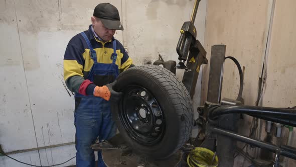 Technician Worker Checks the Tire on Wheel in Garage