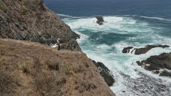 Woman with Blonde Hair on Top of Cliff Admiring Beautiful Turquoise Waters