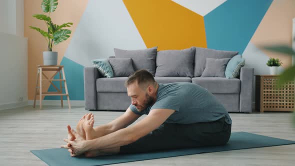 Flexible Man Stretching Body in Seated Position Doing Forward Bend To Legs