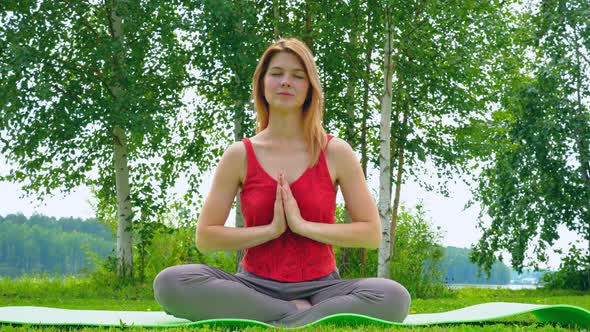Young Beautiful Girl Practices Yoga in Nature.