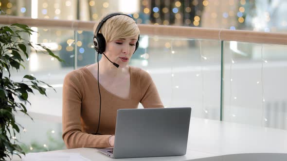 Middle Aged Adult 40s Business Woman in Headset Microphone Talking at Laptop Web Camera Consultation