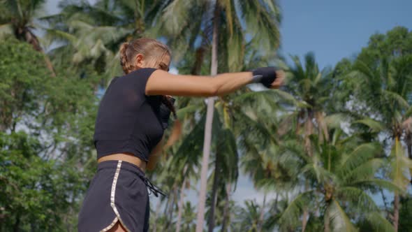 Closeup of Young Pretty Boxer in Black Sportswear with Hands in Fingerless Gloves Practicing Boxing