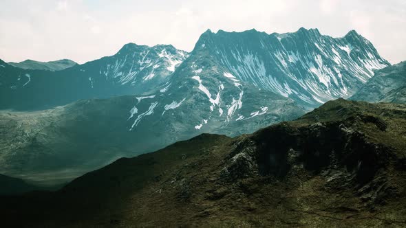 Sunny Landscape with Views of Snowcapped Mountains and Meadow