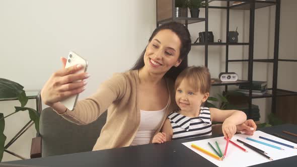 Mother and Her Little Daughter Take Selfies While Working in the Home Office