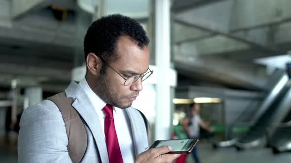 Businessman with Backpack Talking By Smartphone in Airport