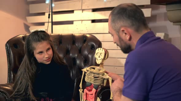 Father Explaining His Younger Daughter the Bone Structure of Human Body Showing on Skeleton