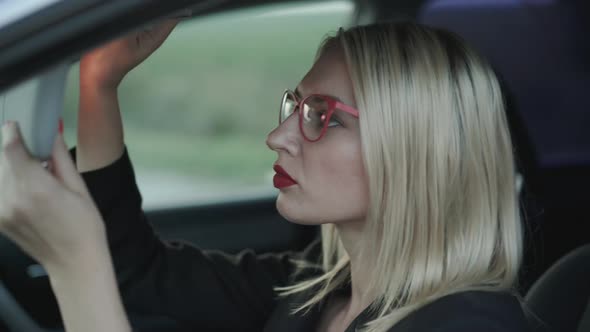 Glamorous Blonde Applying the Red Lipstick at Mirror in Car