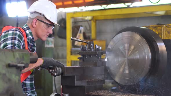 Male engineer metalworker operating work on lathe machine,