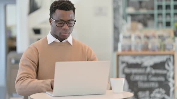 Creative African Man Looking at Camera While Working on Laptop