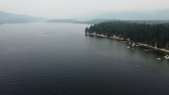 Counterclockwise drone shot of the shore and water at Lake Payette in McCall, Idaho on a very smoky