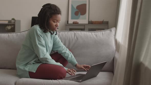 Cheerful African Woman Messaging with Friend Using Laptop