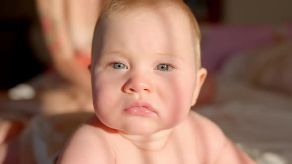 A Nice Little Caucasian Newborn Baby is Funny Smiling Lying at the Back in the Child Crib