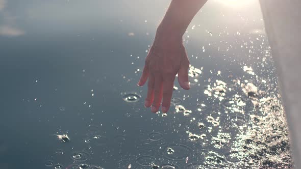 A Male's Hand Hanging on the Edge of a Sailing Boat Feeling the Splash of Water