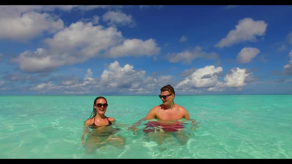 Young couple tan on tranquil tourist beach voyage by clear ocean with bright sand background of the 