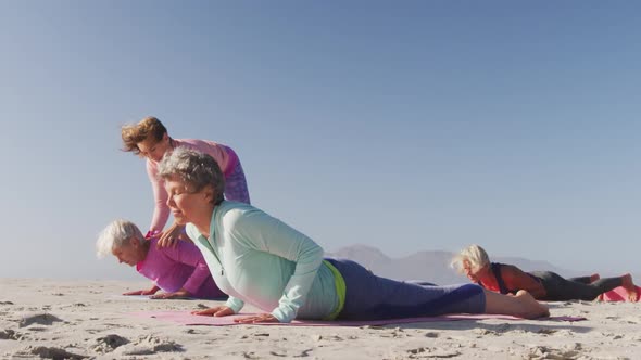 Yoga teacher teaching yoga to senior women at the beach