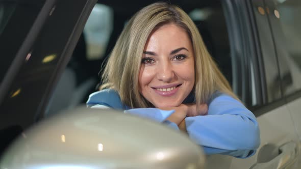 Closeup Attractive Caucasian Woman Looking at Camera Leaning on Car Door Smiling