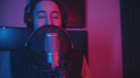 A Smiling Man in Headphones Recording His Song in the Studio