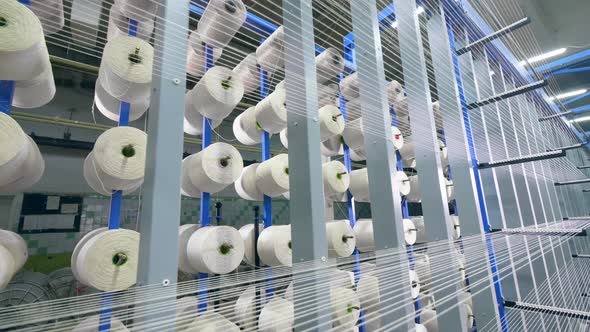 Rows of White Strings Coiling Onto Spools at a Textile Plant.