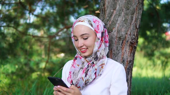 Muslim Girl Spending Outdoor Leisure with Cell