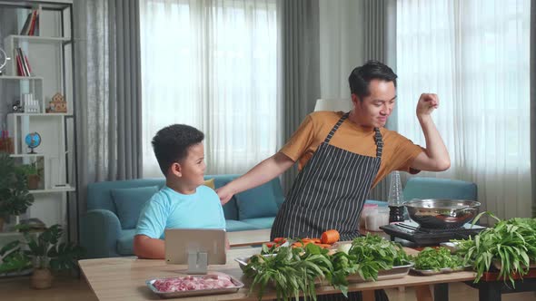 Man Father And Little Child Son Looking Tablet While Cooking Together, Funny Father Putting Salt