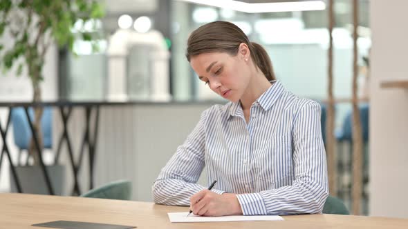 Writing Young Woman Doing Paperwork in Office 