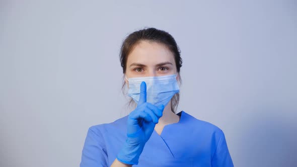 A Doctor in a Medical Mask Holds a Finger in Front of His Mouth a Gesture of Silence or Secretion